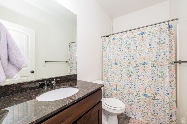 Full bath featuring a shower with curtain, vanity, and toilet | Image 19