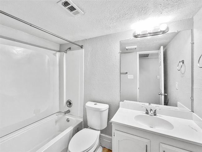 Full bath featuring a textured wall, a textured ceiling, vanity, and washtub / shower combination | Image 5