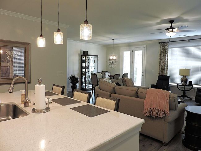 Living area with crown molding, a ceiling fan, and dark wood-type flooring | Image 10