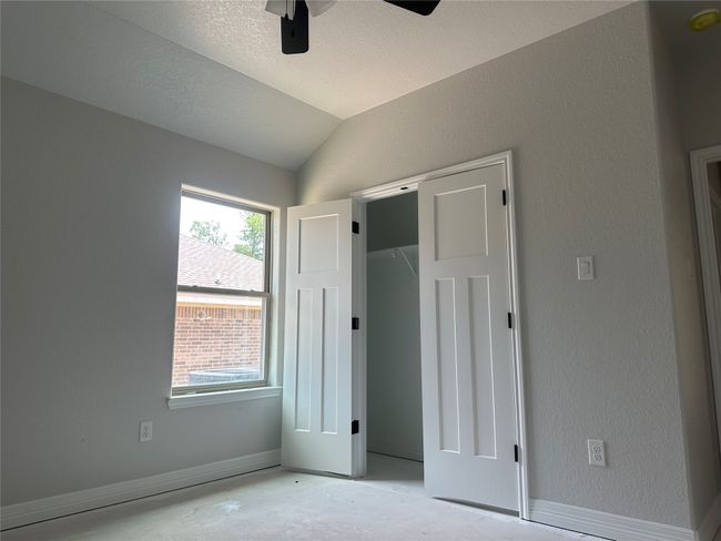 Unfurnished bedroom featuring baseboards, ceiling fan, a textured wall, and vaulted ceiling | Image 19
