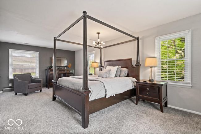 carpeted bedroom featuring a chandelier, multiple windows, and baseboards | Image 22