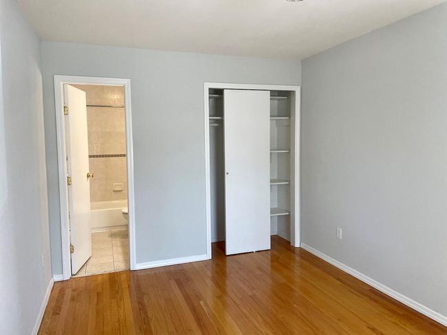 Unfurnished bedroom with wood finished floors, ensuite bathroom, baseboards, and a closet | Image 11