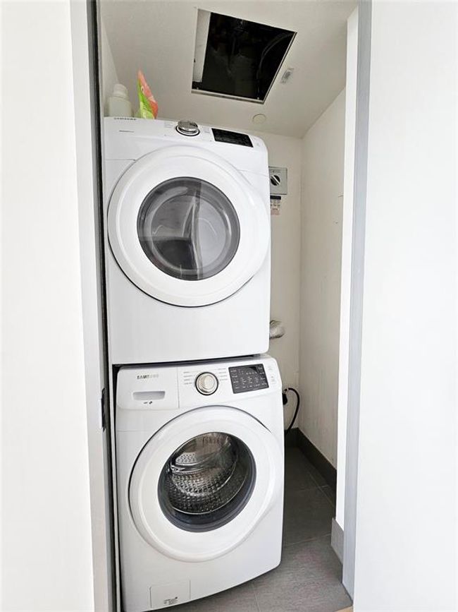 Laundry room with stacked washing maching and dryer, tile patterned floors, and laundry area | Image 10
