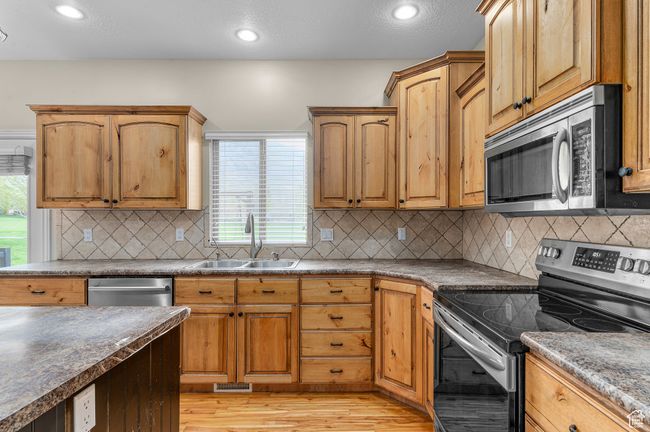 Kitchen with recessed lighting, a sink, light wood-style flooring, backsplash, and appliances with stainless steel finishes | Image 5