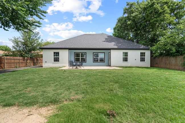Rear view of house with a fenced backyard, brick siding, a shingled roof, and a patio area | Image 36