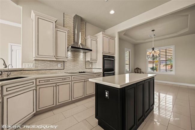 Kitchen with a sink, wall chimney range hood, light countertops, and black appliances | Image 16
