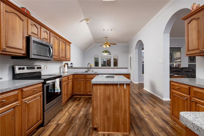 Kitchen featuring a ceiling fan, a sink, stainless steel appliances, a peninsula, and a kitchen island | Image 21
