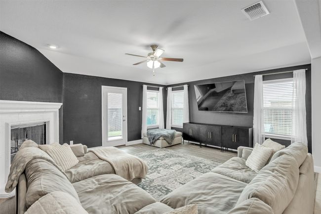 Living room with ceiling fan, wood finished floors, healthy amount of natural light, and a fireplace | Image 12