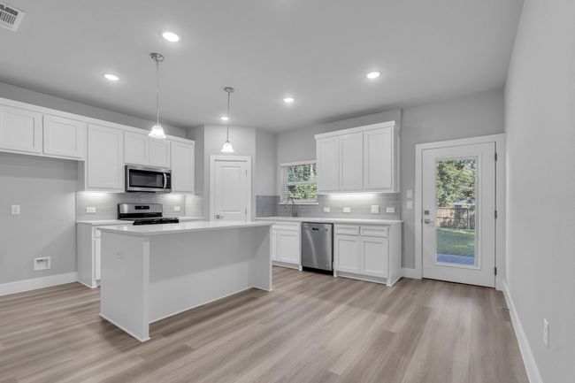 Kitchen featuring white cabinetry, light countertops, backsplash, and appliances with stainless steel finishes | Image 11