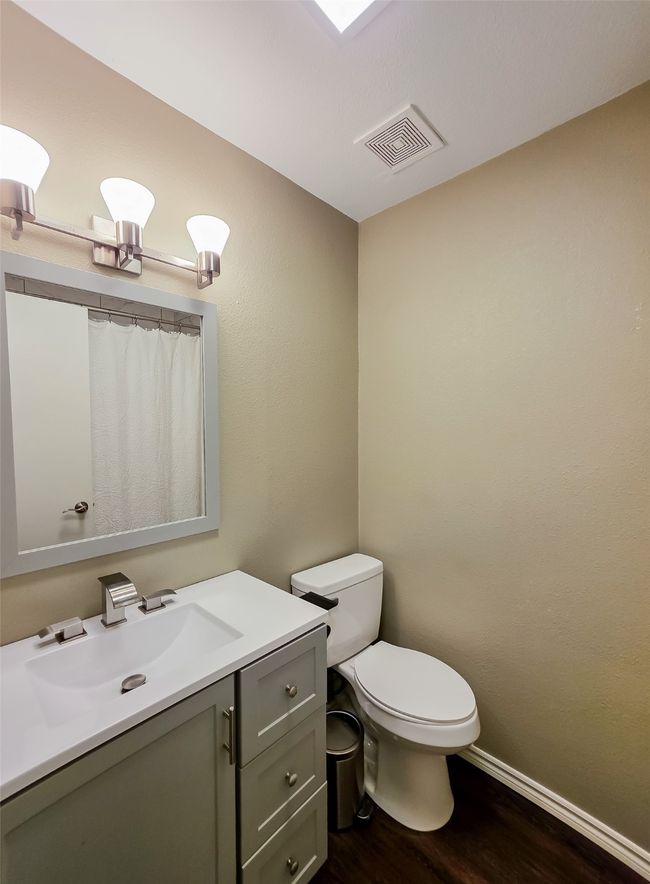 Bathroom with wood finished floors, toilet, vanity, baseboards, and a shower with curtain | Image 13