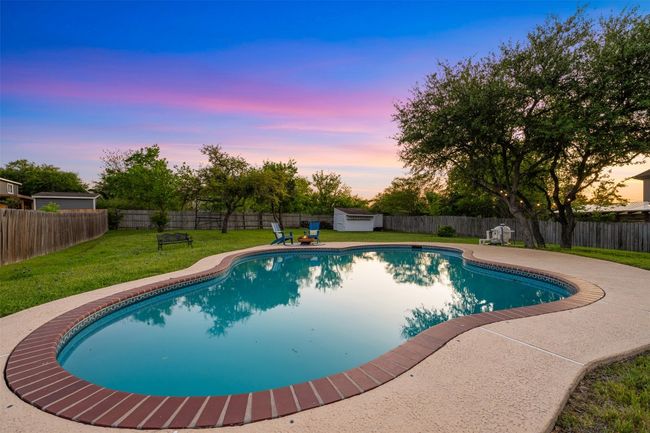 Pool at dusk with a storage shed, an outbuilding, a fenced in pool, and a lawn | Image 36