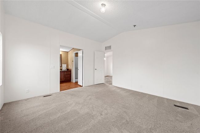 Primary Bedroom Unfurnished bedroom featuring lofted ceiling, carpet floors, and ensuite bathroom | Image 15