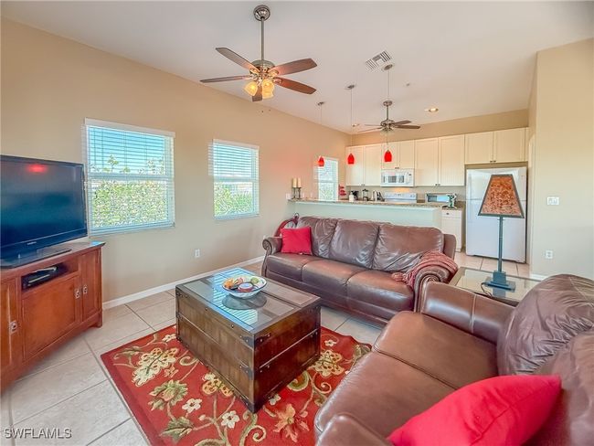 Living room featuring a ceiling fan, visible vents, baseboards, and light tile patterned floors | Image 12