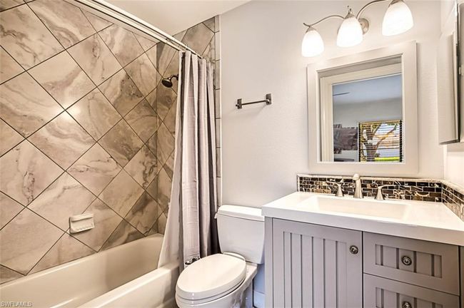 Full bathroom with shower / bath combo with shower curtain, toilet, decorative backsplash, and vanity | Image 37