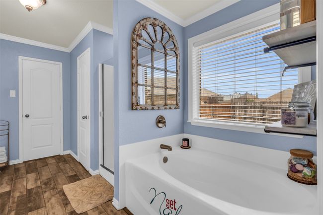 Bathroom with wood-type flooring, shower with separate bathtub, and crown molding | Image 9