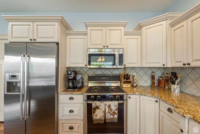 Kitchen with stainless steel appliances, cream cabinetry, and light stone countertops | Image 15