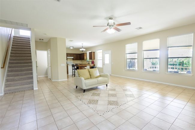 Living room featuring a ceiling fan, visible vents, stairway, light tile patterned flooring, and baseboards | Image 8