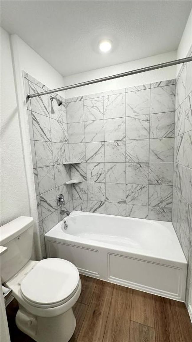 Bathroom featuring toilet, shower / tub combination, and wood finished floors | Image 6