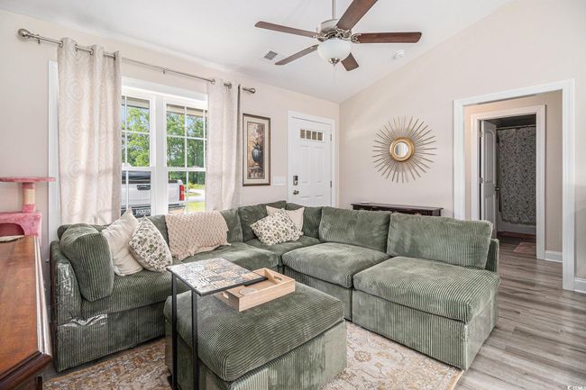 Living area with a ceiling fan, lofted ceiling, wood finished floors, and baseboards | Image 6