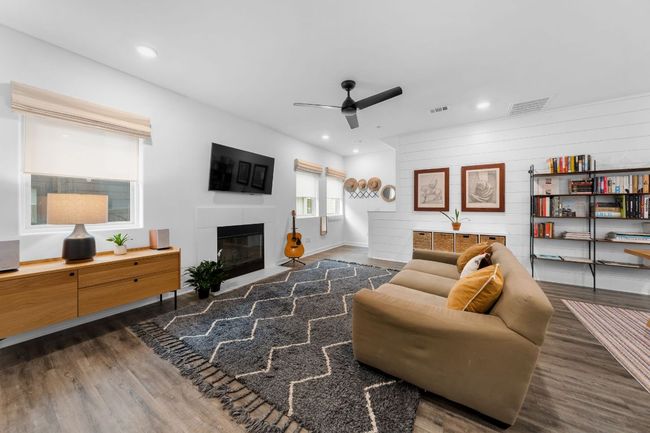 Living area with visible vents, a fireplace with flush hearth, ceiling fan, and wood finished floors | Image 7