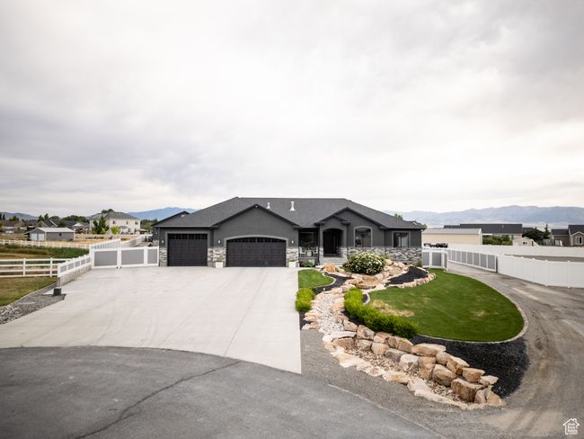 View of front of property with an attached garage, driveway, a mountain view, and stone siding | Image 9