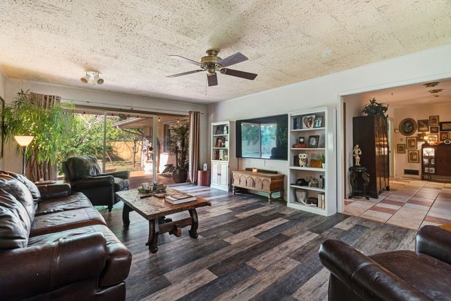 Living room with a ceiling fan, wood finished floors, and a textured ceiling | Image 11