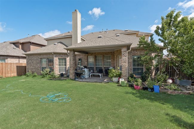 Back of property with a patio area, a shingled roof, brick siding, and a chimney | Image 31