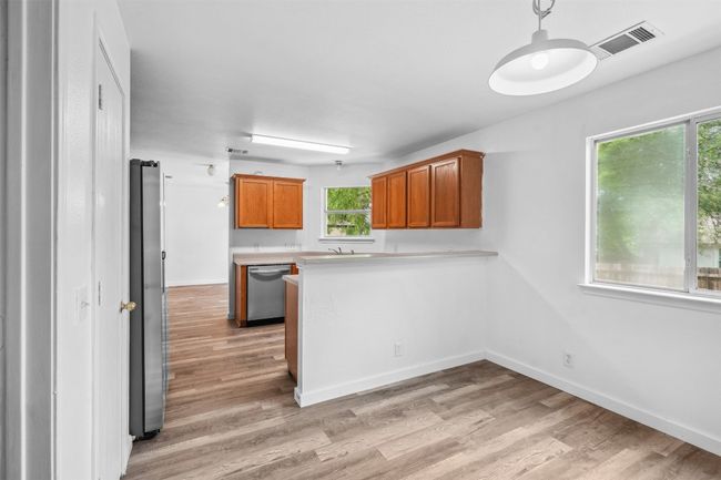 Kitchen featuring visible vents, a peninsula, appliances with stainless steel finishes, and light wood-type flooring | Image 13
