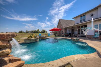 Large concrete patio with lovely pool with waterfall and spa. | Image 3