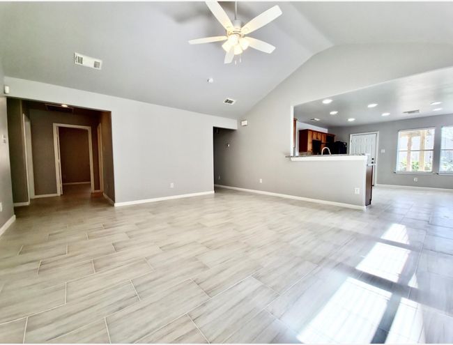 Unfurnished living room featuring vaulted ceiling and a ceiling fan | Image 5