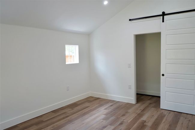 Unfurnished room with vaulted ceiling, light wood-type flooring, a barn door, and recessed lighting | Image 18