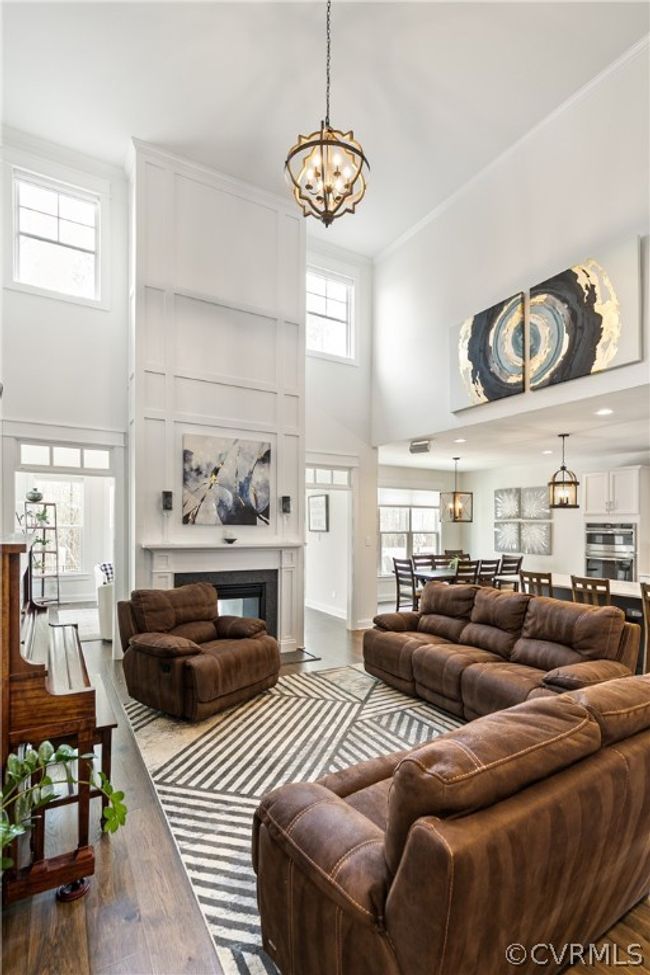 Living room featuring plenty of natural light, hardwood / wood-style floors, a towering ceiling, and a chandelier | Image 9