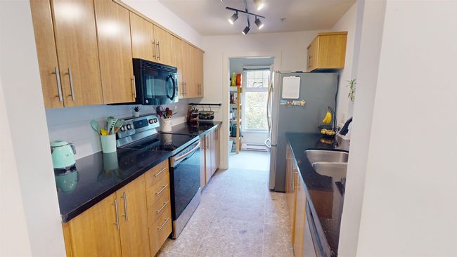 Kitchen featuring a baseboard heating unit, stainless steel appliances, light brown cabinetry, a sink, and decorative backsplash | Image 4