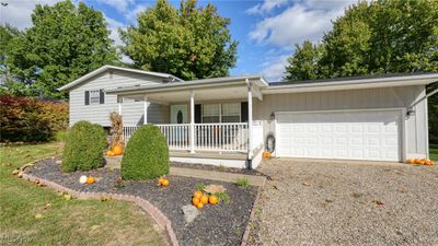 Ranch-style house featuring covered porch and a garage | Image 1