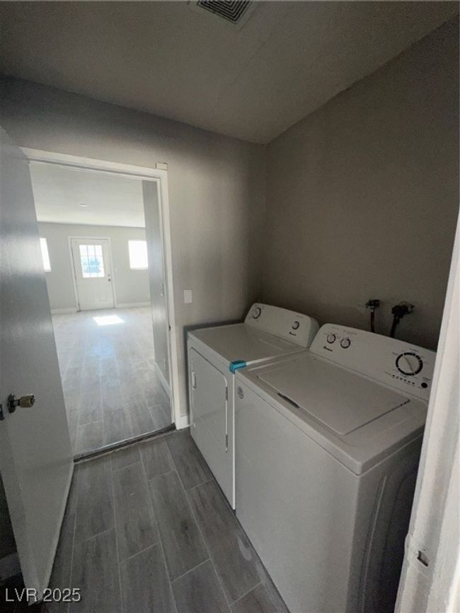 Clothes washing area featuring independent washer and dryer, wood finish floors, and baseboards | Image 8