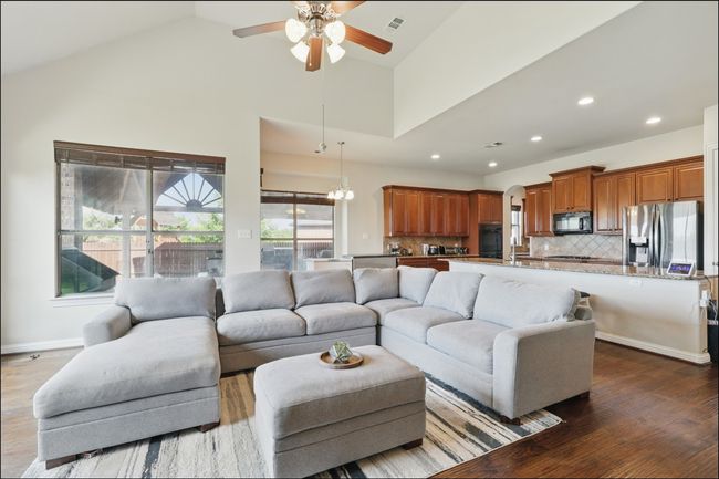 Living room with arched walkways, ceiling fan, dark wood finished floors, recessed lighting, and a towering ceiling | Image 17