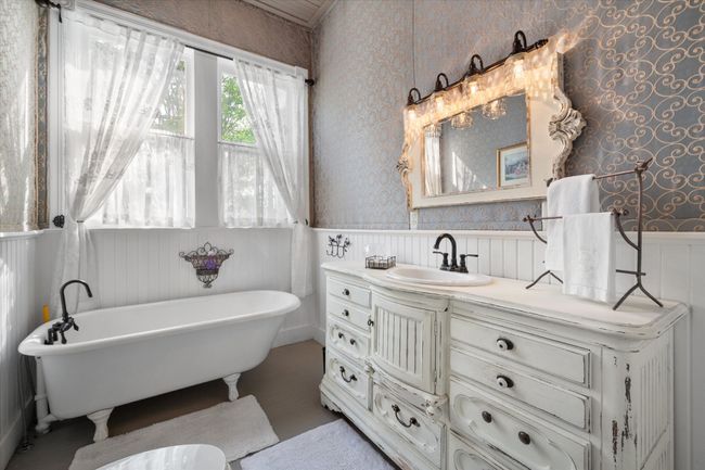 Downstairs full bath with wallpapered walls, a wainscoted wall, vanity, and a freestanding bath | Image 19