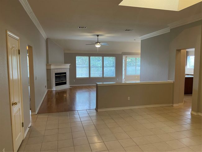 Unfurnished living room featuring crown molding, ceiling fan, light tile patterned floors, and a tile fireplace | Image 6