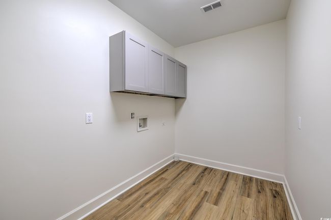 Laundry area with cabinet space, hookup for a washing machine, and light wood-style floors | Image 23