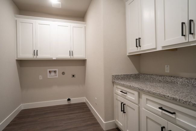 Laundry area with cabinet space, hookup for an electric dryer, washer hookup, dark wood-type flooring, and baseboards | Image 20
