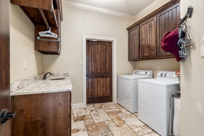 Laundry room featuring cabinet space, washer and dryer, and stone tile flooring | Image 32