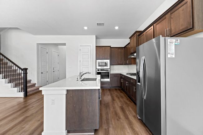 Kitchen with stainless steel appliances, a sink, dark wood finished floors, light countertops, and recessed lighting | Image 12
