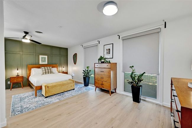 An expansive primary bedroom with floor-to-ceiling windows, electric window shades, and Vinyl Plank flooring throughout. | Image 16