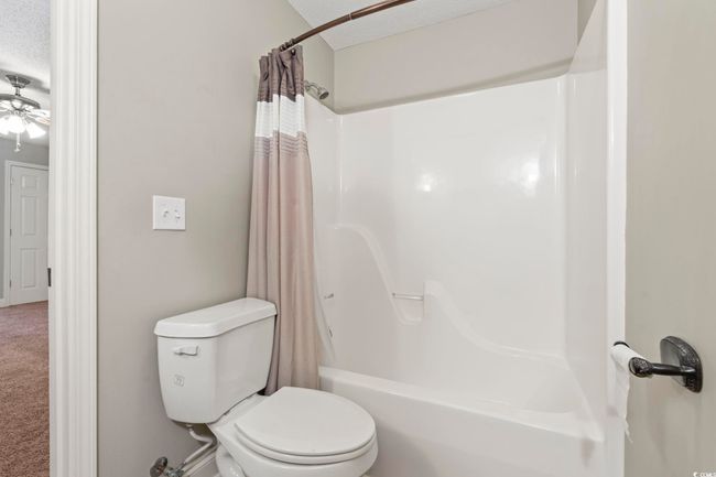 Full bathroom with toilet, shower / tub combo with curtain, ceiling fan, and a textured ceiling | Image 29
