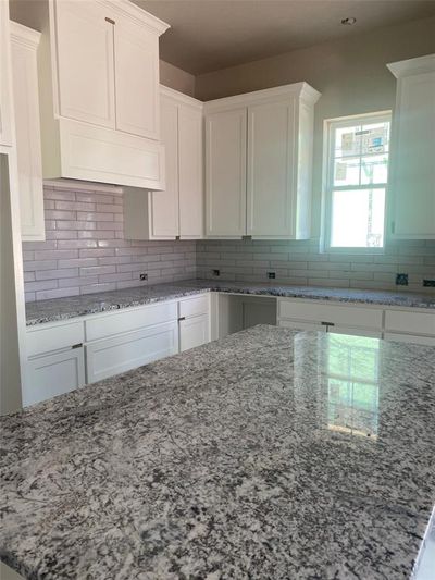 Kitchen featuring white cabinetry, light stone countertops, and decorative backsplash | Image 3