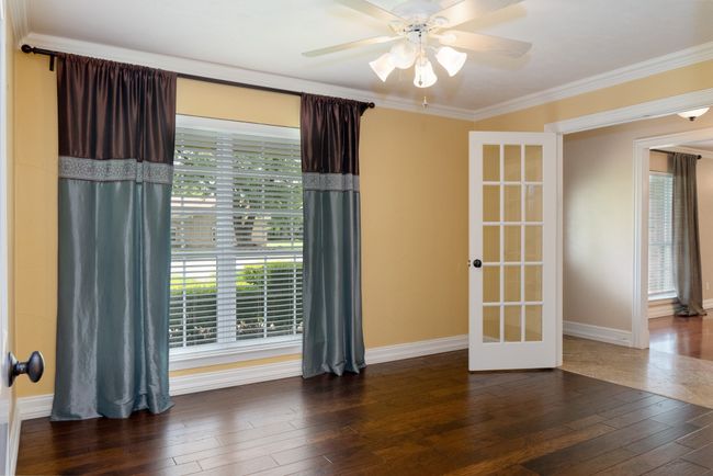 Empty room with french doors, dark wood finished floors, crown molding, healthy amount of natural light, and a ceiling fan | Image 7