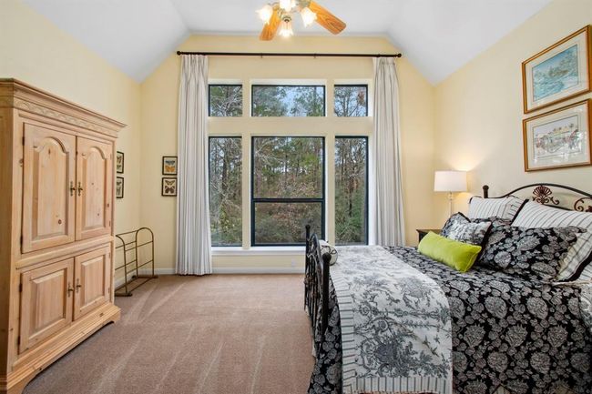 This spacious third bedroom suite boasts soaring ceilings and an unobstructed, panoramic view of nature through the floor to ceiling windows. Elegant blackout draperies facilitate both sleeping-in and privacy, ensuring guests are comfortable. | Image 31