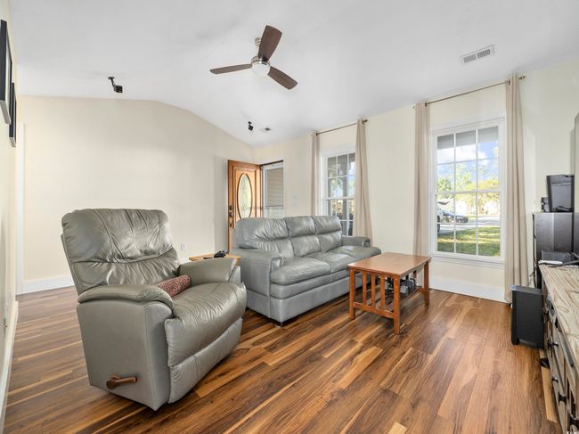 Living room with visible vents, lofted ceiling, baseboards, ceiling fan, and dark wood-style floors | Image 5