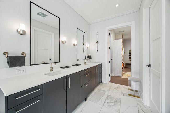 [Primary Bath] Double sinks, quartz countertop and upgraded brass fixtures accentuated by large, sleek mirrors and chrome sconces | Image 24