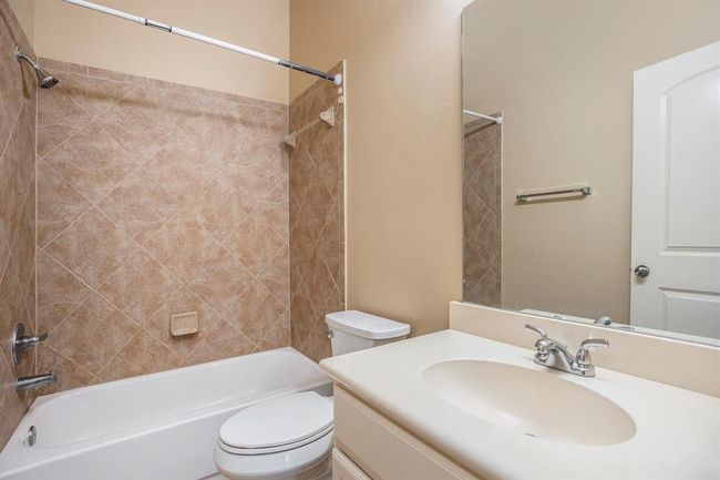 This full bathroom is conveniently located between the two front bedrooms and features a tub/shower combo with tile surround, a large vanity with ample counter space, and a full-size mirror. Neutral finishes make it easy to personalize. | Image 25